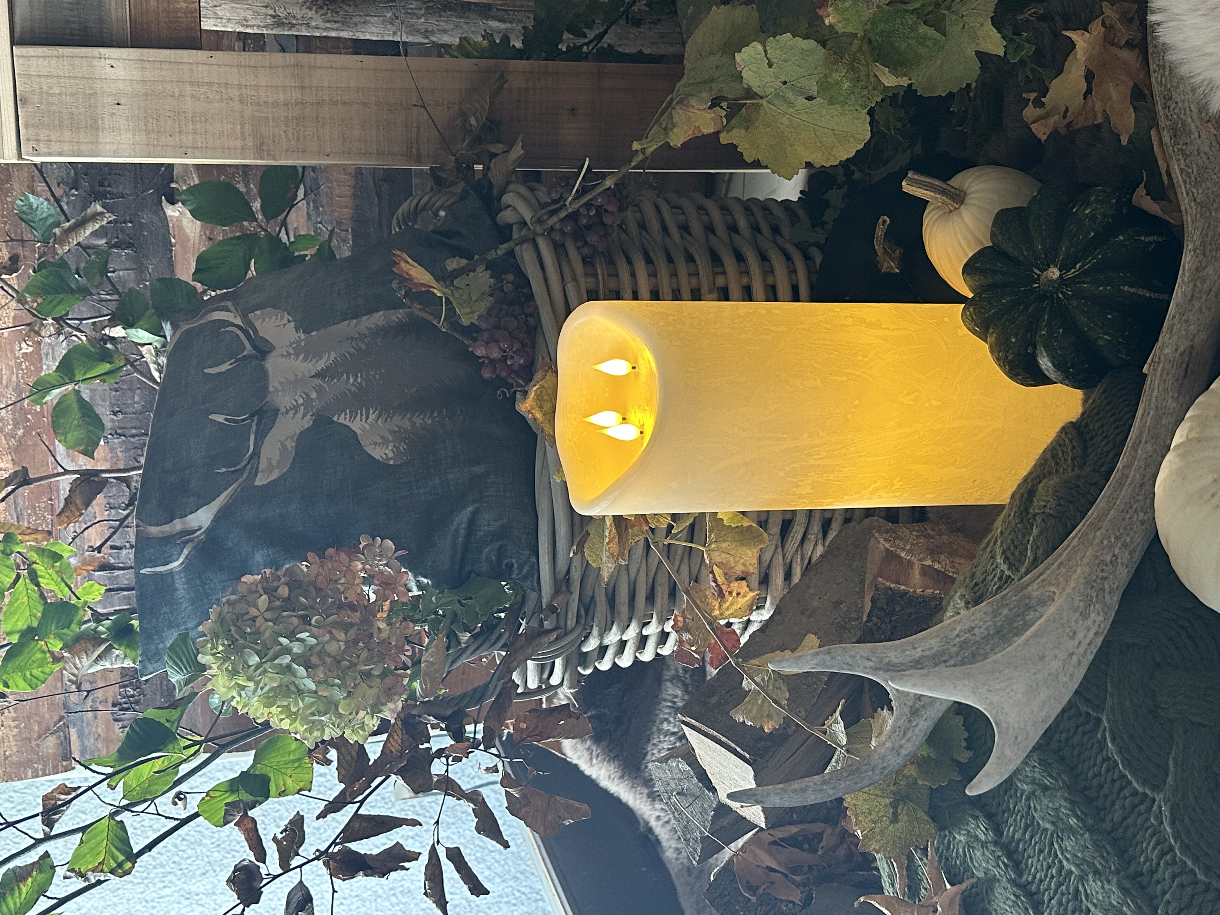Herbstdeko: LED‑Kerze, Hirschkissen und Zierkürbisse als rustikale Landhausdekoration