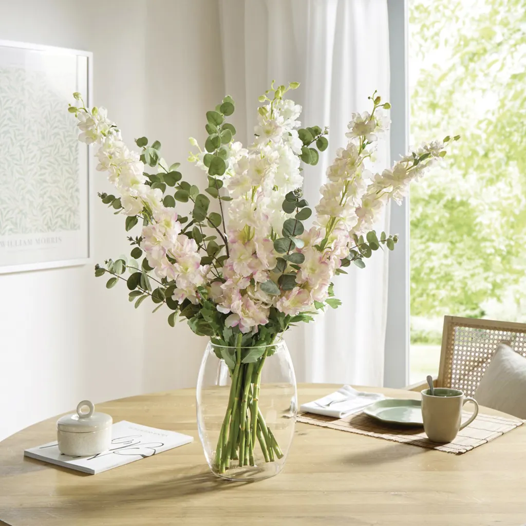 Heller Blumenstrauß aus weiß‑roséfarbigen Blüten und Eukalyptus in Glasvase