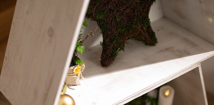 Weihnachtsdeko: Rentier aus Moos auf weißem Holzregal als natürliche Festtagsdekoration