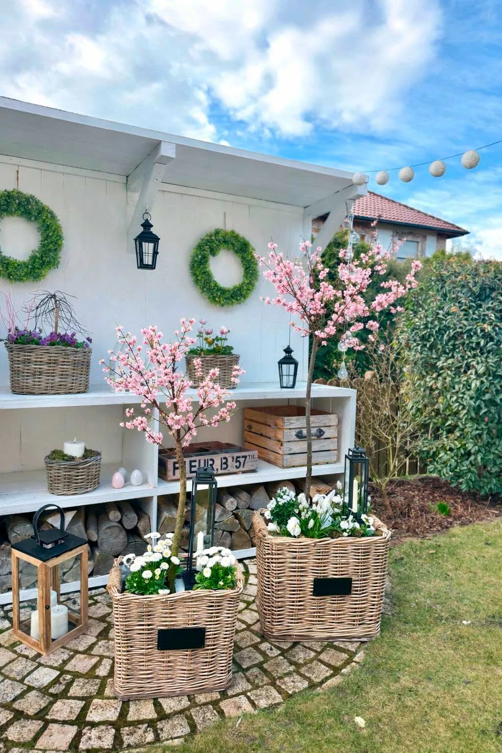 Gartendeko: große Weidenkörbe mit Kirschblüten und Frühlingsblumen als Außendekoration
