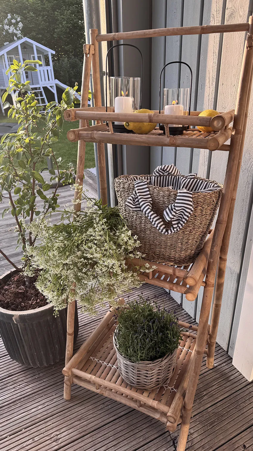 Gartendeko: Bambusregal mit Pflanzen, Korb und Laternen im Außenbereich auf Terrasse